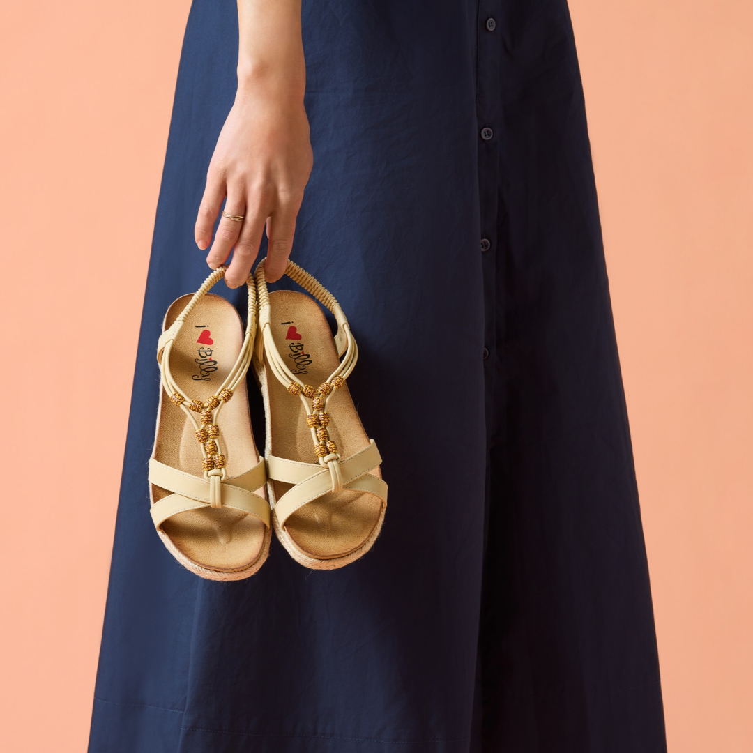 Woman holding gold sandals from Williams Shoes